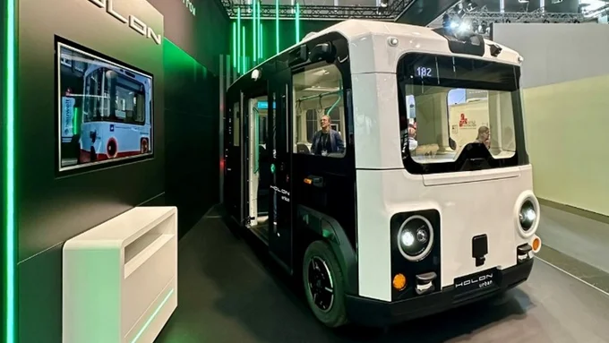 Das automatisierte Shuttle Farhezug des Herstellers Holon auf einem Messestand schräg von vorne abfotografiert.