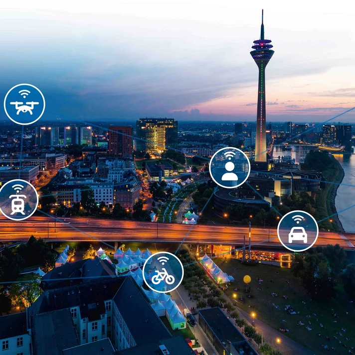 Panorama von Düsseldorf bei Nacht mit Icons für Auto, Bus, Bahn, Fahrrad, Schiff, Flugzeug, Drohne und Nutzer, die ein vernetztes Mobilitätssystem darstellen.