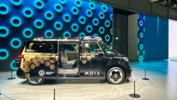 Ansicht eines Shuttles von Moia von der Seite, ein Großraumfahrzeug in schwraz mit goldenen geogafischen Formen dekoriert.