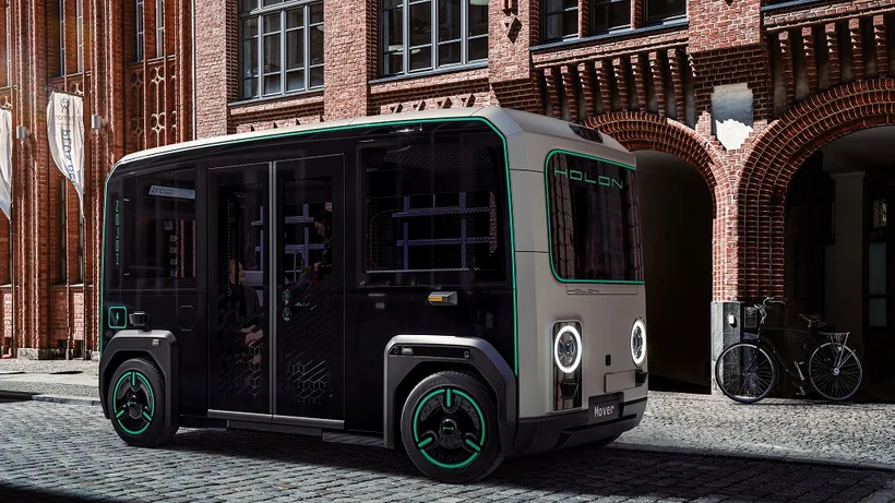 Autonomer Holon Mover parkt auf Kopfsteinpflaster vor historischem Gebäude.