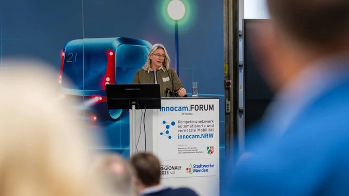 Frau spricht beim innocam.FORUM am Rednerpult, Publikum im Vordergrund leicht unscharf.