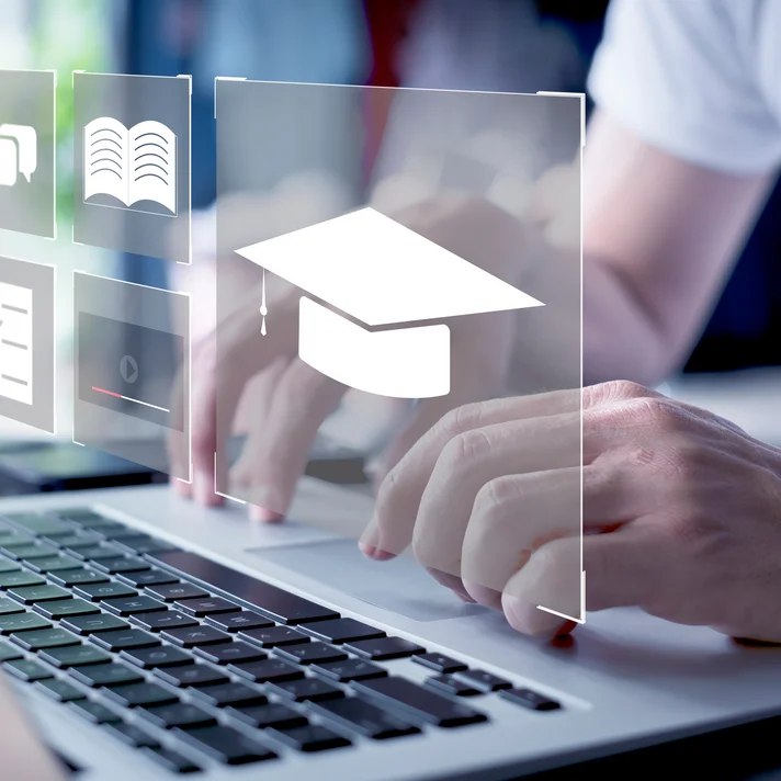Eine Person tippt auf einem Laptop, während Symbole für digitales Lernen und Bildung über dem Bildschirm eingeblendet sind.