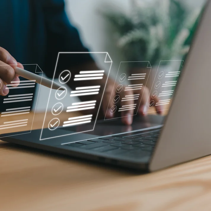 Eine Person arbeitet am Laptop, während darüber digitale Checklisten mit abgehakten Aufgaben eingeblendet sind.