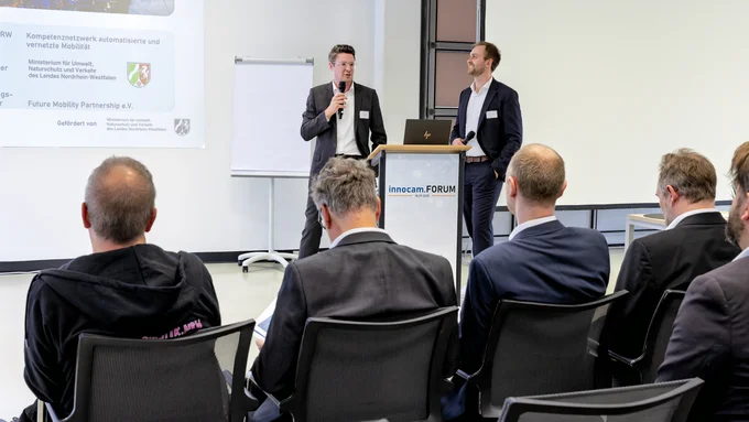 Zwei Referenten sprechen bei einer Fachveranstaltung vor einem Publikum über automatisierte und vernetzte Mobilität.