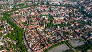 uftaufnahme der Stadt Münster in Nordrhein-Westfalen mit dem Dom im Zentrum, umgeben von historischen Gebäuden, Straßenringen und Grünflächen.