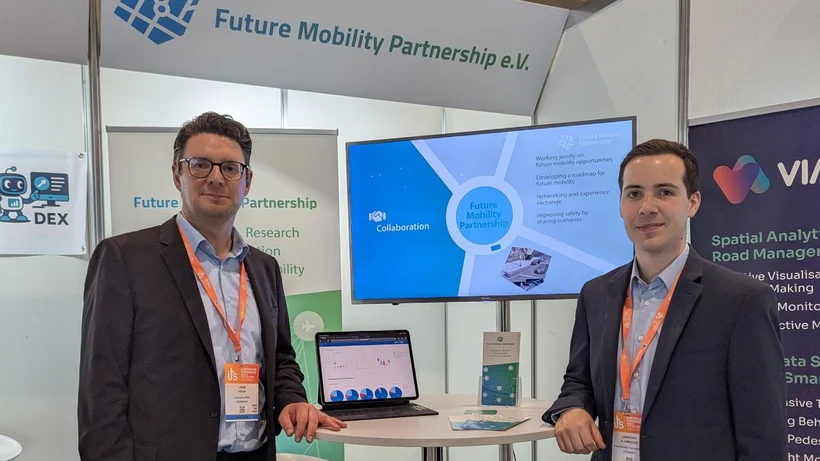 Zwei Männer stehen auf einem Messestand am Tisch