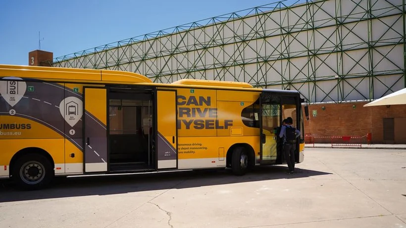 Ein gelber autonomfahrender Bus steht vor der Messehalle