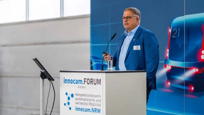 Mann spricht am Rednerpult mit Bildschirmpräsentation zum Thema automatisierte Mobilität.