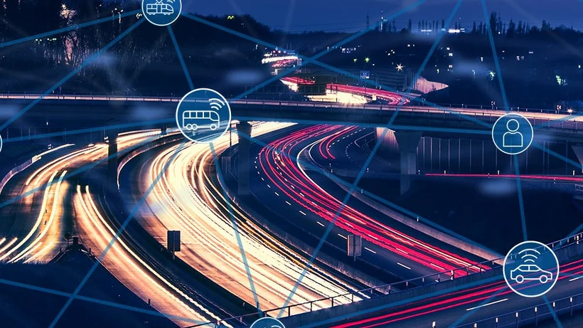 Nachtaufnahme eines Autobahnkreuzes mit Lichtspuren fahrender Fahrzeuge, überlagert von blauen Linien und Symbolen für vernetzte Mobilität wie Auto, Bus, Fahrrad und Nutzer.        ChatGPT fragen