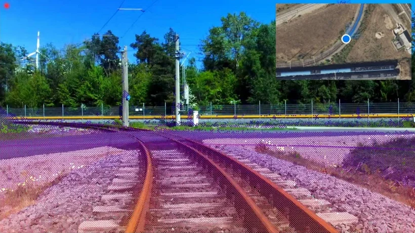 Blick auf zwei sich verzweigenden Bahngleise vor bewaldeter Kulisse mit einem kleinen Kartenausschnitt oben rechts.