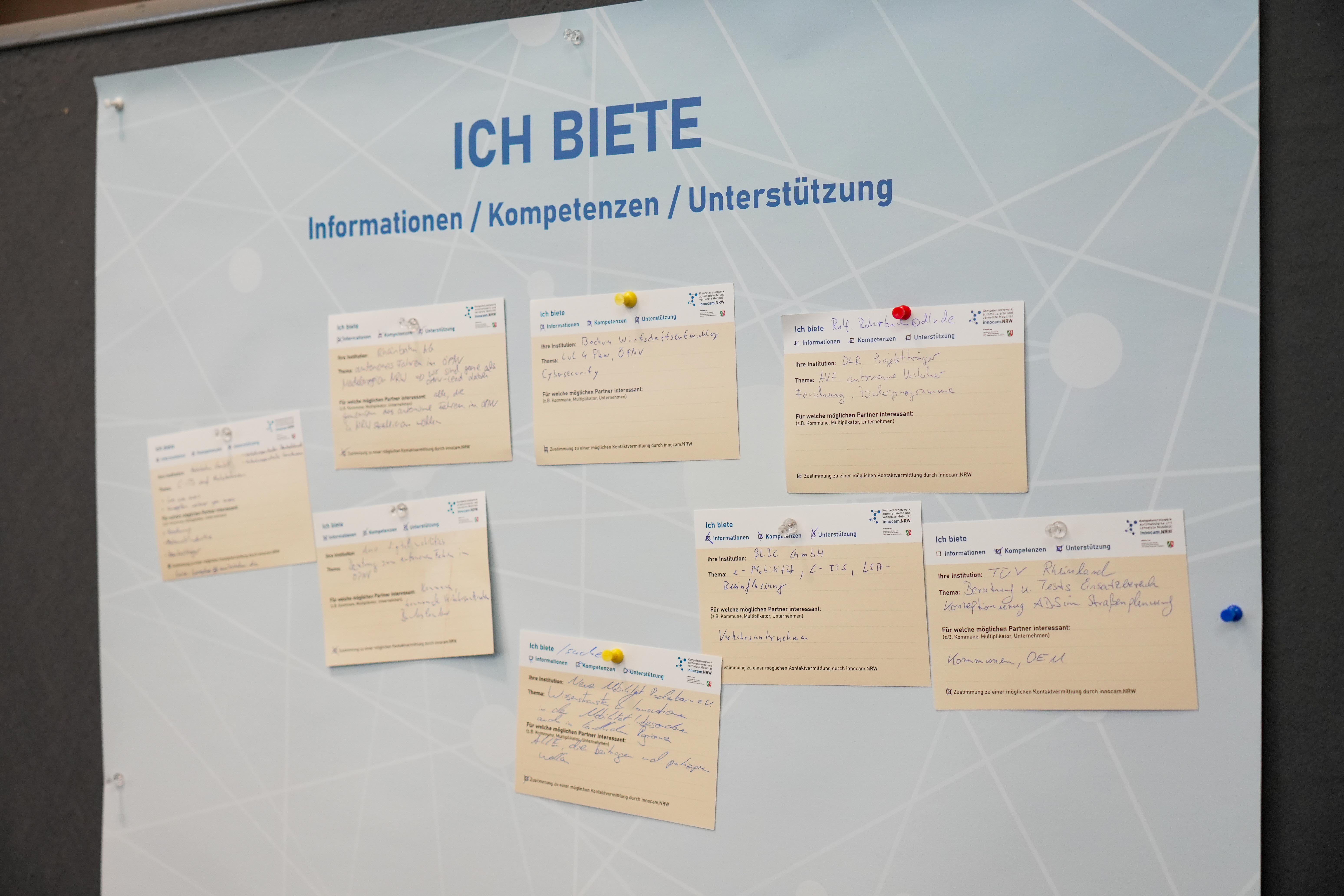 Tafel mit dem Titel 'ICH BIETE' und mehreren beige Zetteln, die Informationen, Kompetenzen und Unterstützung beschreiben, befestigt mit farbigen Pinnnadeln.