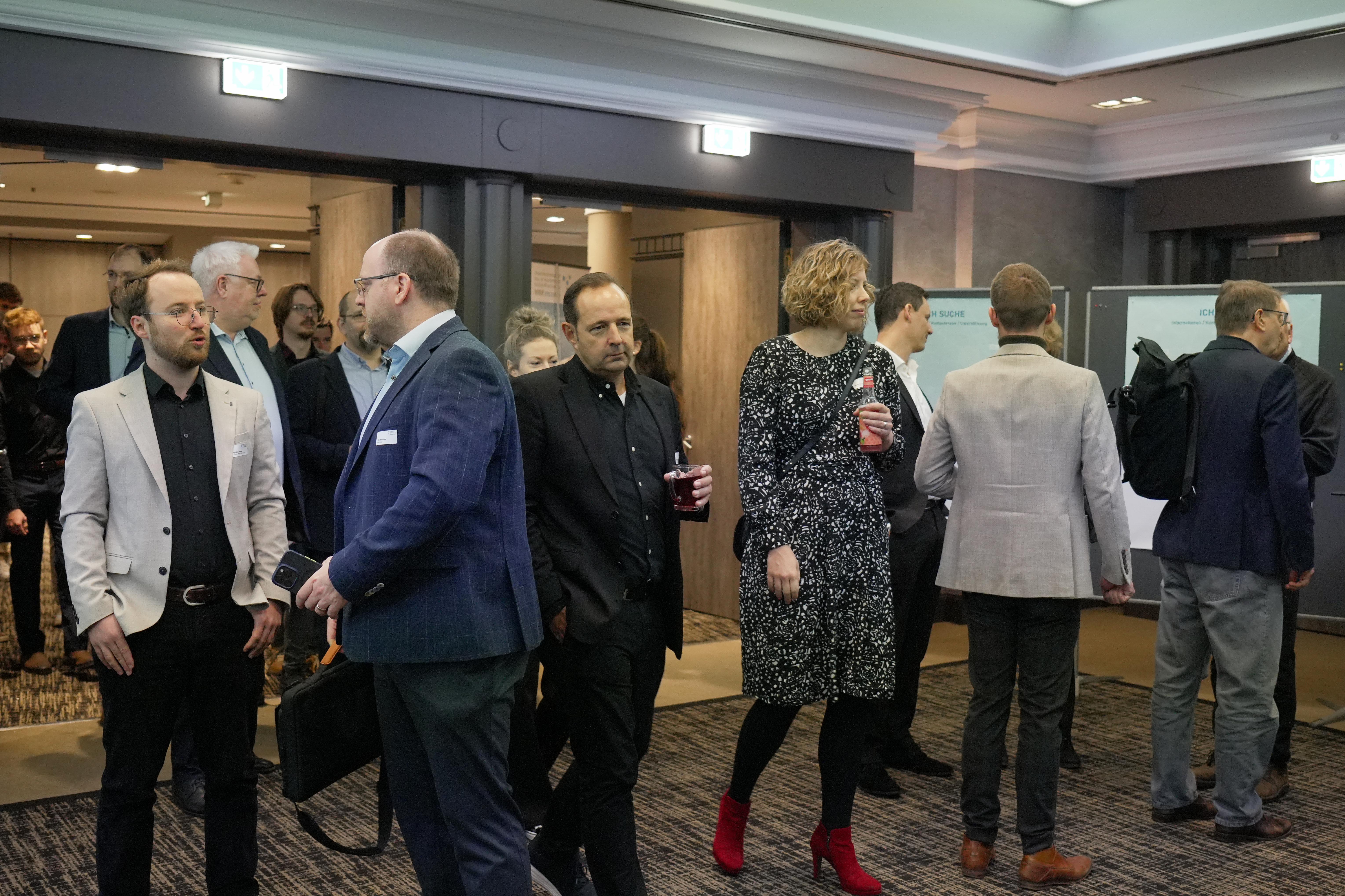 Mehrere Personen in Businesskleidung stehen und unterhalten sich in einem Konferenzraum beim innocam.NRW Mobility Meeting.